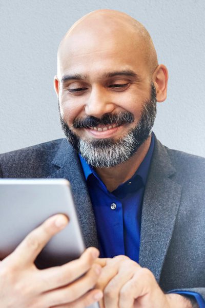 Man smiling while using tablet