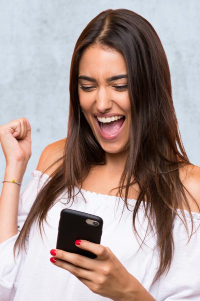 Woman cheers while looking at smart phone screen