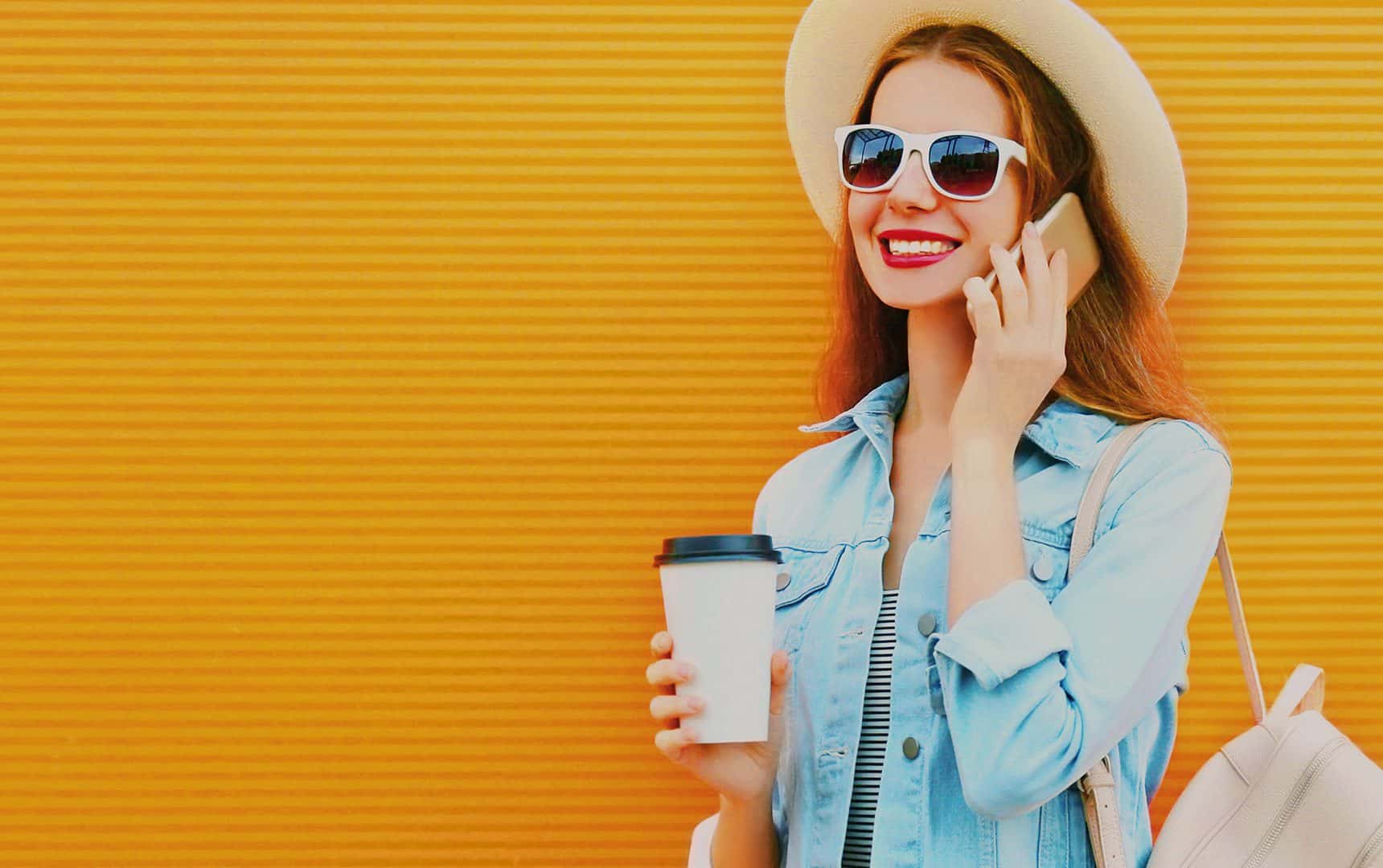 Woman smiling while on the phone against orange background