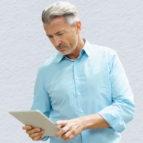Man looks intently at tablet he is holding