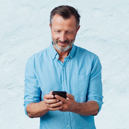 Man smiling while looking at smartphone