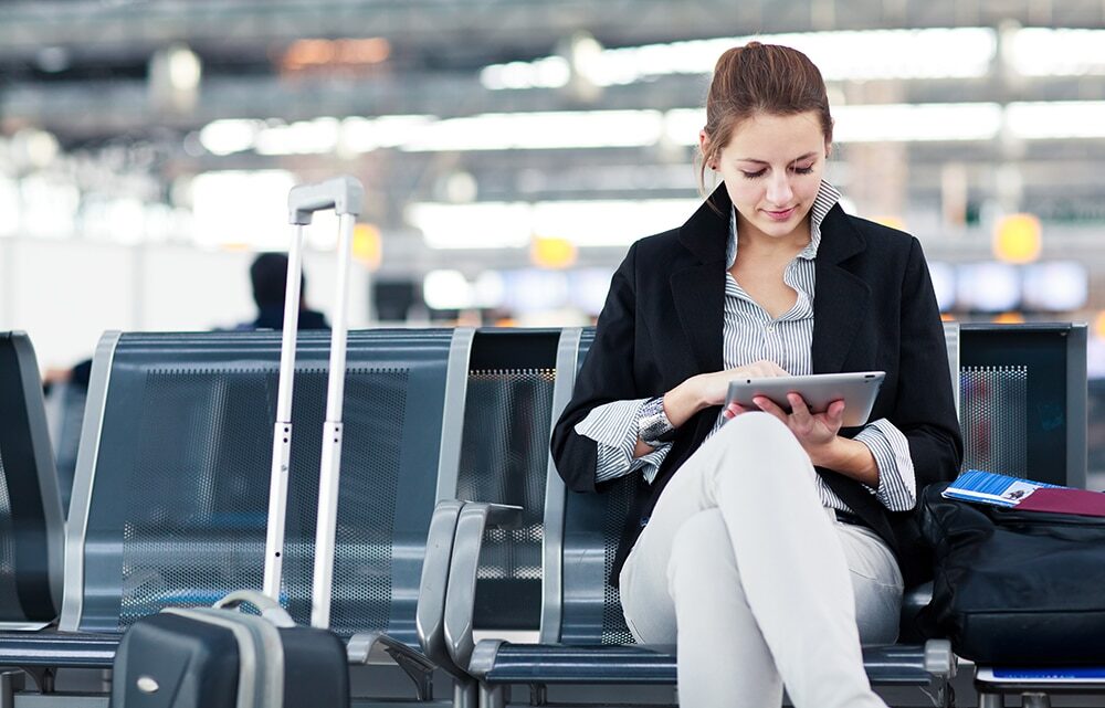 Woman sitting in airport lounge busy in her tablet