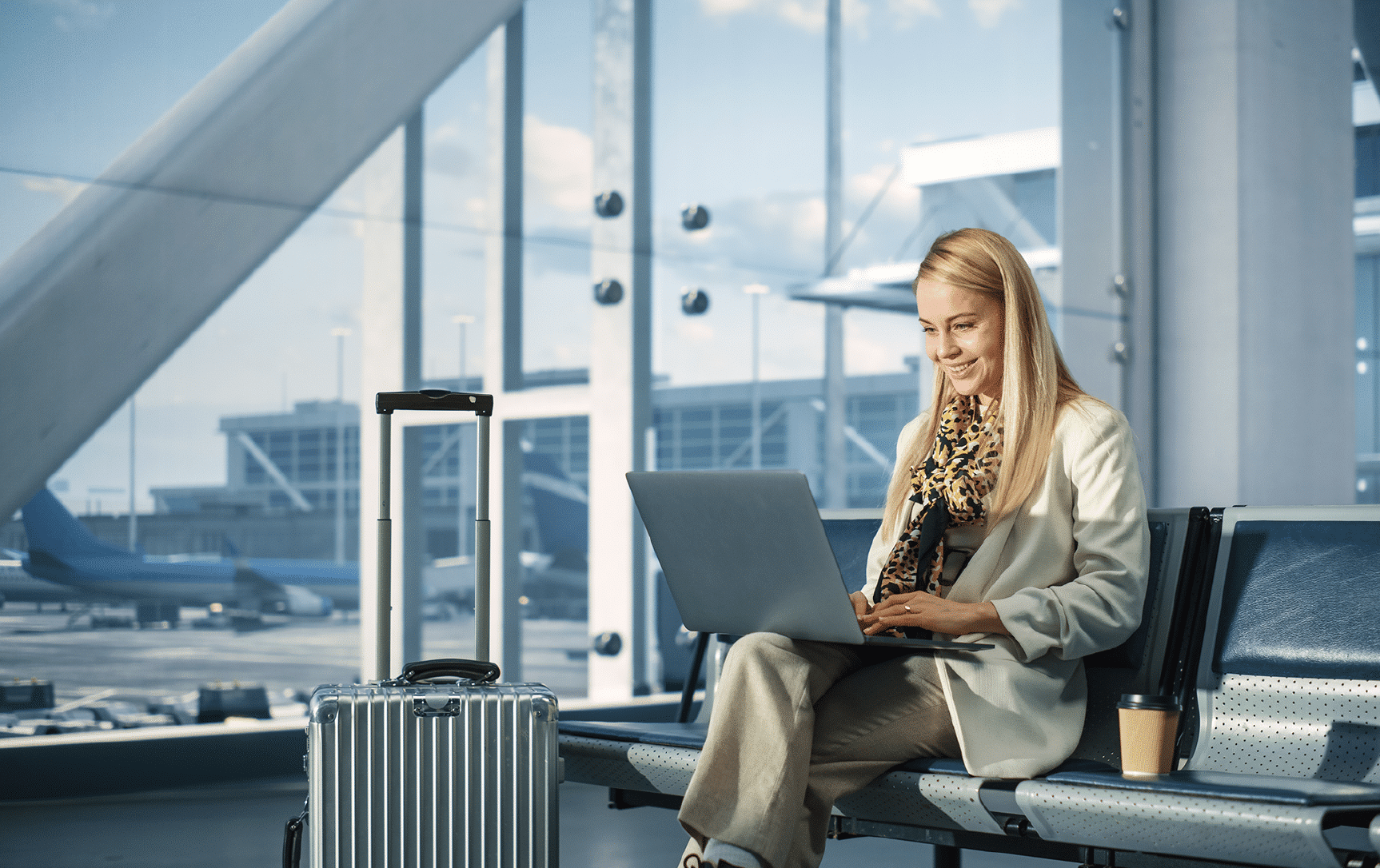 Woman at the airport lounge working on laptop and smiling