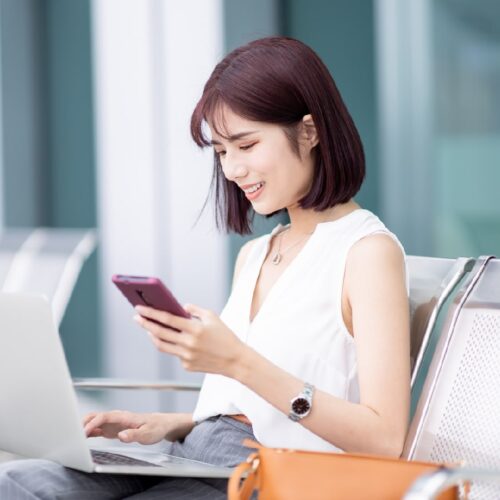 Woman with mobile phone in hand and laptop in the lap