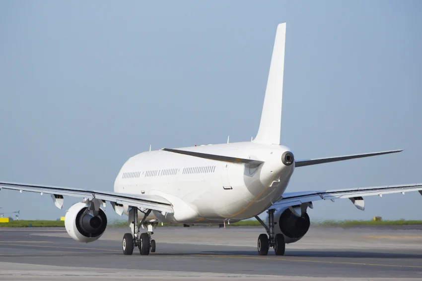 Accelya FLX Order Accounting: Rear view of a commercial airplane taxiing on the runway under clear skies, highlighting streamlined aviation operations.