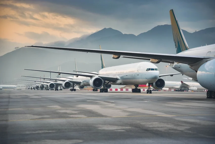 Accelya NDC solution: A row of commercial airplanes lined up on a runway against a backdrop of misty mountains, highlighting aviation efficiency.